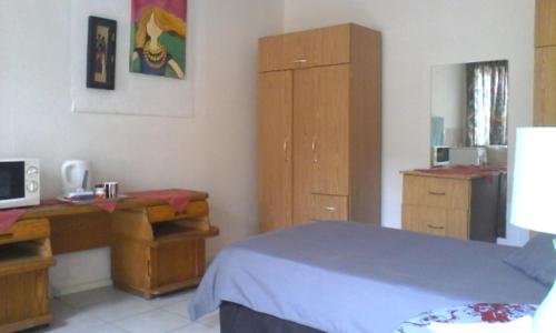 a bedroom with a bed and a desk and a cabinet at Germiston Residential Motel in Germiston
