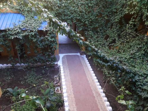 a garden with a red brick walkway with ivy at Hôtel restaurant CMG in Ilakaka