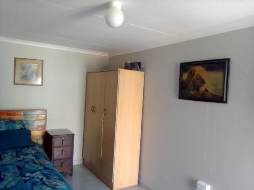 a bedroom with a bed and a cabinet and a painting at Germiston Residential Motel in Germiston