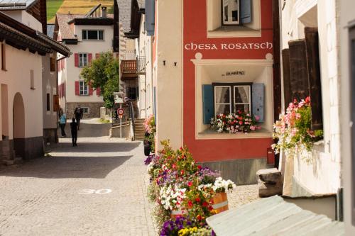 a street in a town with flowers on the side of a building at Hotel Chesa Rosatsch - Home of Food in Celerina