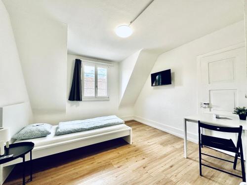 a white room with a bed and a desk at Monteurzimmer ZIMMERzuVERMIETEN in Balsthal Solothurn in Balsthal