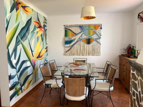 a dining room with a glass table and chairs at Casa com Cor in Zambujeira do Mar