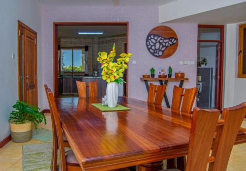 a wooden dining room table with a vase of flowers at ZaNaKri Homes ;A Great Panorama of Indian Ocean in Mombasa