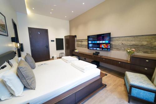 a hotel room with a bed and a flat screen tv at Central Bed & Breakfast in Kolkata