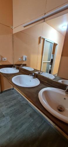 łazienka z 4 umywalkami i dużym lustrem w obiekcie Dajti Paradise Hostel 
