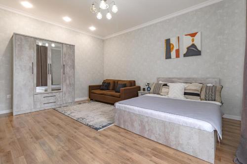a bedroom with a large bed and a couch at Апартаменты в ЖК Apple City in Astana