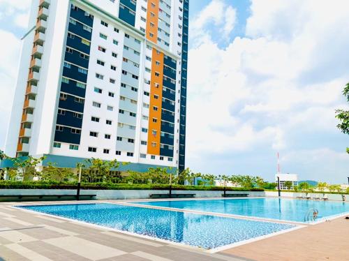 a swimming pool in front of a tall building at UMAR HOMESTAY - Alanis KLIA in Sepang