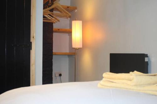 een slaapkamer met een bed met een lamp en een aantal handdoeken bij Turners Albert Road Basement Apartment in Colne