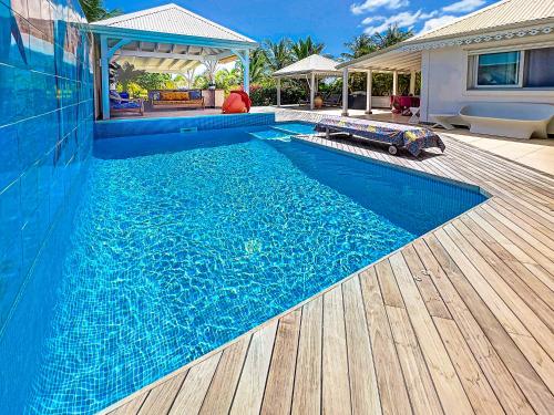 une grande piscine bleue à côté d'une maison dans l'établissement Villa Marie, swimming pool, beach, pontoon and jacuzzi, all private, à Baie Nettlé