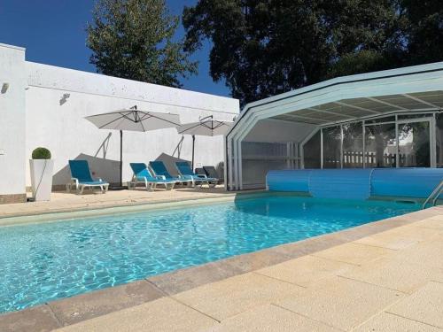 a swimming pool with chairs and umbrellas next to a building at Casa do Pinheiro in Fiães