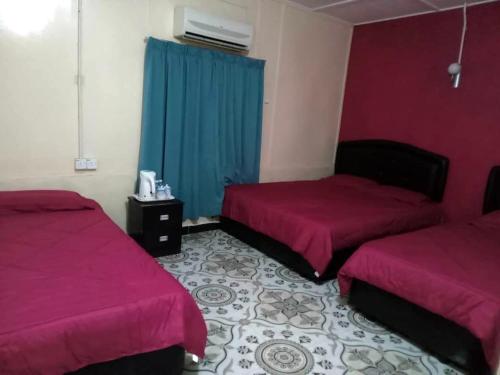 2 łóżka w pokoju z fioletowymi ścianami w obiekcie D view hill hotel w mieście Kuala Tahan