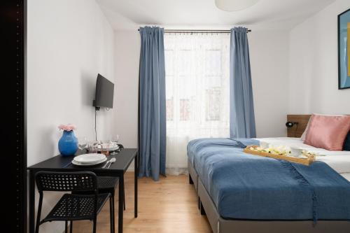 a bedroom with a bed and a desk and a bed and a window at Cozy Studio Kwiatowa Poznań by Renters in Poznań
