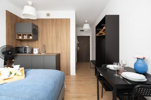 a room with a bed and a table and a kitchen at Cozy Studio Kwiatowa Poznań by Renters in Poznań