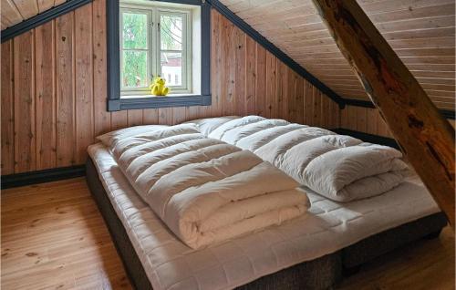 Bett in einem Zimmer mit Holzwänden und einem Fenster in der Unterkunft Stunning Home In Eidsberg With Kitchen 