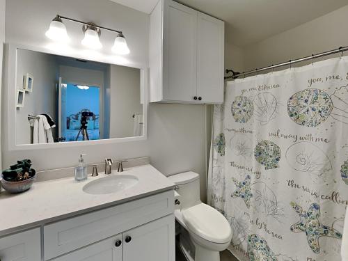 a bathroom with a toilet and a sink and a shower curtain at Canal Royale in Rockport