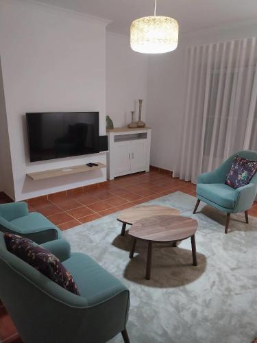 a living room with two chairs and a table and a tv at Casa com Alma by LovelyStay in Fátima