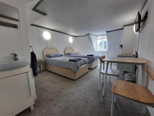 1 dormitorio con 2 camas, lavamanos y mesa en Dawlish Lawn View, en Dawlish