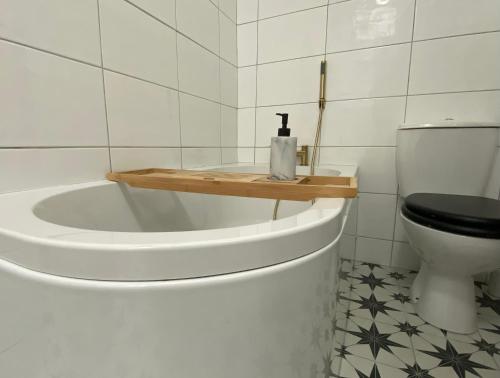 a bathroom with a toilet and a wooden shelf on a tub at Yellow door cottage in Moville