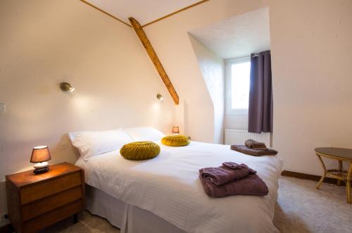 Un dormitorio con una cama blanca con dos almohadas encima. en Traditional Brittany Home, en Quessoy