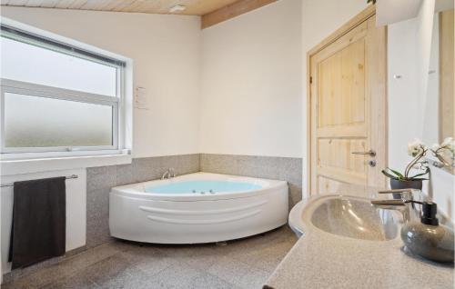 ein Bad mit einer Badewanne, einem Waschbecken und einem Fenster in der Unterkunft Cozy Home In Vinderup With House Sea View in Vinderup