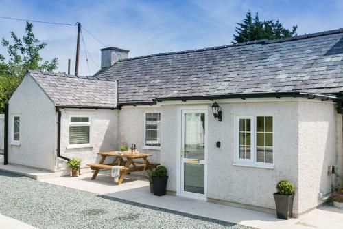 a white cottage with a picnic table in front of it at Tyddyn Waen in Llanddona