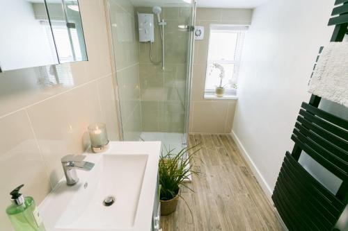 a white bathroom with a sink and a shower at Tyddyn Waen in Llanddona