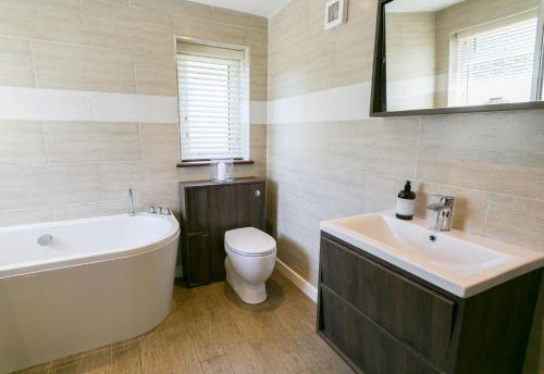 a bathroom with a tub and a toilet and a sink at Tyddyn Waen in Llanddona
