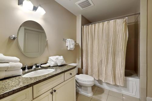 een badkamer met een wastafel, een toilet en een spiegel bij Wharf #506 in Orange Beach