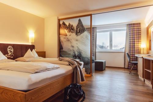 a hotel room with a bed and a large window at Hotel Römerhof Superior in Obertauern