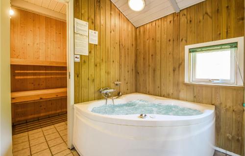 La salle de bains en bois est pourvue d'une baignoire et d'une fenêtre. dans l'établissement Beautiful Home In Brkop With 3 Bedrooms, Sauna And Wifi, à Brejning