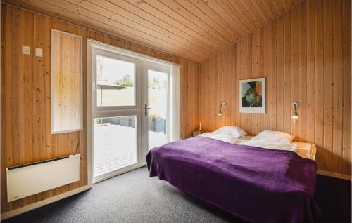 a bedroom with a purple bed in a wooden wall at 4 Bedroom Nice Home In Ejstrupholm in Krejbjerg