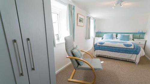 a bedroom with a bed and a chair in it at Borth Bach in Rhosneigr