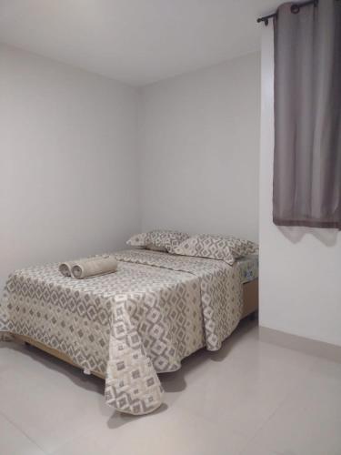 a bed in a white room with a bedskirtspectspectspectspects at Lindo apto praia do bessa in João Pessoa