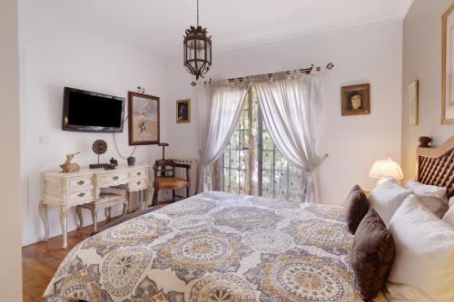 een slaapkamer met een bed, een bureau en een televisie bij Little Paradise 25 min from Lisbon in Azeitao