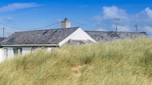 a house sitting on top of a hill with tall grass at Borth Bach in Rhosneigr