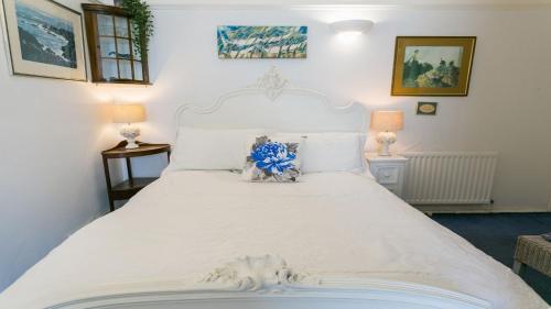 a large white bed with a blue flower on it at Bro Dawel in Rhosneigr