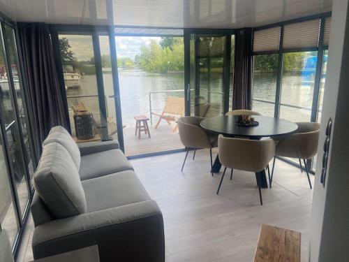 uma sala de estar com um sofá, uma mesa e cadeiras em La Mare Houseboat em Nederhorst den Berg