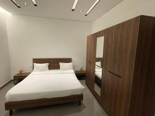 a bedroom with a large bed and a mirror at LADAN APARTMENT in Al-ʿUla