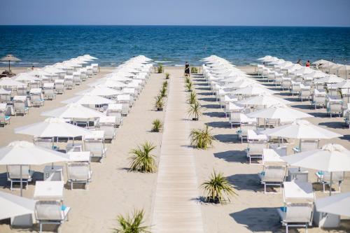 a row of white umbrellas and chairs on a beach at Hotel Saraceno Resort with Private Beach in Milano Marittima