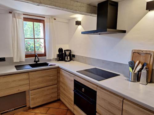 cocina con armarios de madera, fregadero y ventana en Romantic-Louveteaux-en-Provence****, en Saint-Pierre