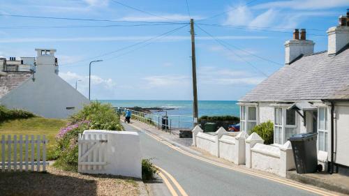 an empty street with houses and the ocean at Brig y Don in Rhosneigr
