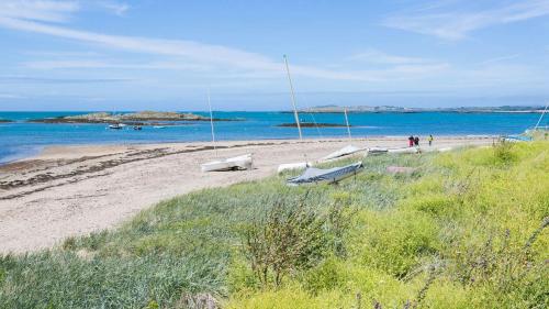 a beach with two benches and the ocean at Brig y Don in Rhosneigr