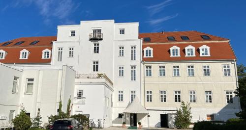 un grand bâtiment blanc avec un toit rouge dans l'établissement Hotel "Friedrich-Franz-Palais", à Bad Doberan