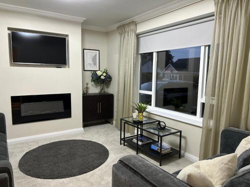 a living room with a couch and a tv and a window at Pine View Holiday Home in Newcastle