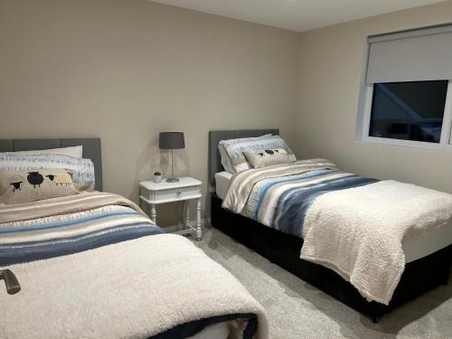 a bedroom with two beds and a window at Pine View Holiday Home in Newcastle