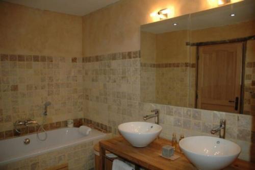 une salle de bain avec deux lavabos, une baignoire et un miroir dans l'établissement Périgourdine du 18ième siècle rénovée avec soin, à Rouffignac-Saint-Cernin-de-Reilhac