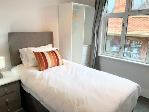 1 dormitorio con 1 cama blanca y ventana en Lovely 2BR Cottage in Stansted, en Stansted Mountfitchet
