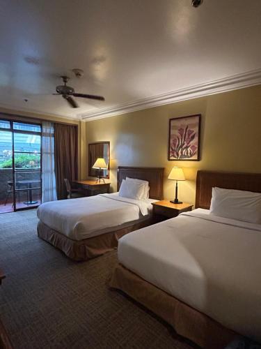 een hotelkamer met 2 bedden en een raam bij Private Unit at The Camp John Hay Manor in Baguio