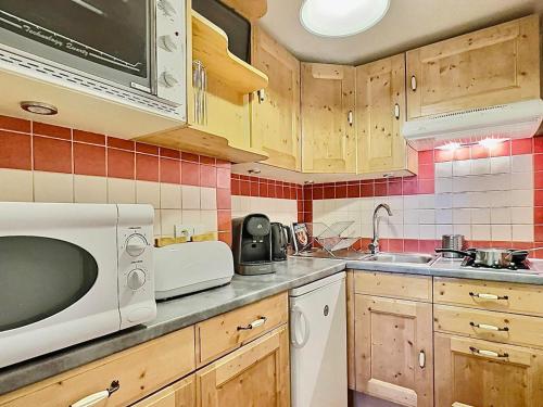 une cuisine avec un micro-ondes et un évier dans l'établissement Tignes Le Lac - Appt cosy 32m², 4 pers, Pied des pistes, Sud-Est, Animaux OK, Équipé & Fonctionnel - FR-1-411-149, à Tignes