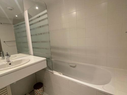 un bagno bianco con lavandino, vasca e specchio di Appartement Méribel, 2 pièces, 4 personnes - FR-1-411-654 a Les Allues